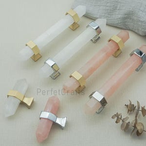 May include: A collection of crystal cabinet pulls in white and pink hues. The pulls have gold and silver metal accents. The text "PerfetcCrafts" is visible in the image.