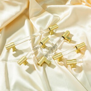 May include: Several cabinet pulls with clear acrylic rods and gold-colored metal hardware. The pulls are arranged on a cream-colored satin fabric. The text "PerfectCrafts" is visible on the fabric.