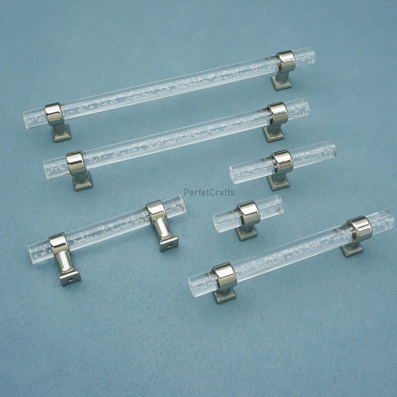 Peut inclure: Poign&eacute;es de meubles en acrylique transparent avec bases en m&eacute;tal argent&eacute;. Les poign&eacute;es pr&eacute;sentent une texture de type bulle &agrave; l'int&eacute;rieur de l'acrylique transparent. Plusieurs poign&eacute;es de diff&eacute;rentes tailles sont pr&eacute;sent&eacute;es sur fond bleu.