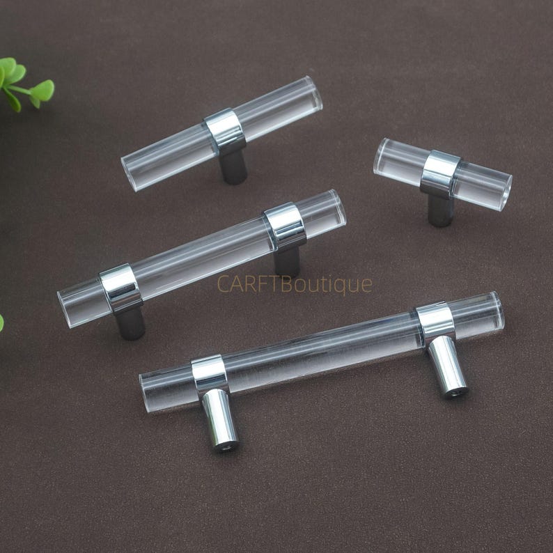 May include: A white ceramic mug with a black handle and the text "But First, Coffee" in a bold, black font. The mug is set against a blurred background, suggesting a cosy setting.