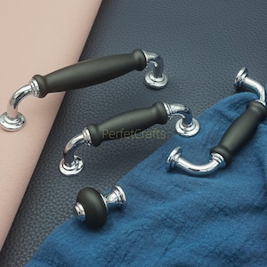 Op de afbeelding: Een verzameling zwarte en chromen kastgrepen en een knop. De grepen hebben een gebogen ontwerp met een zwart middenstuk en chromen accenten. De knop heeft een bijpassend zwart en chroom ontwerp. De tekst "PerfetcCrafts" is zichtbaar.