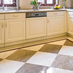 Pu&ograve; includere: Cucina luminosa con mobili color crema e lavastoviglie in acciaio inossidabile. Il pavimento presenta un motivo a scacchi nei toni del grigio e del bianco, incorniciato da un bordo scuro. La cucina ha un lavandino e una finestra.