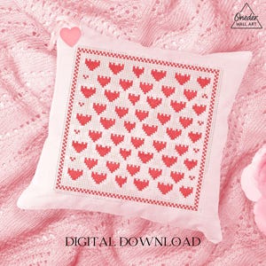 May include: A square, off-white pillow with a cross-stitched pattern of red hearts. The pillow is on a pink knitted surface. The words "DIGITAL DOWNLOAD" are at the bottom of the image.