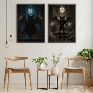 May include: Two framed art prints featuring a black cat dressed as a vampire with bat wings. The cat is in a dark gothic setting with a full moon and candles. The prints are displayed on a white wall with wooden chairs and side tables.