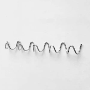 Könnte beinhalten: Eine silberfarbene Wandhakenleiste aus Metall mit einem durchgehenden, sich wiederholenden Spiral- oder Wellendesign. Die Struktur besteht aus einem einzigen Stück gebogenem Draht mit mehreren abgerundeten Schlaufen zum Aufhängen.