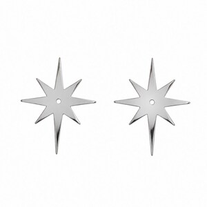 May include: A pair of silver-toned metal earring jackets shaped like eight-pointed stars. Each star features a central circular hole designed to accommodate an earring post, with elongated, sharp points radiating from the center.