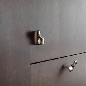 May include: Two polished silver-toned metal cabinet pulls with an organic, asymmetrical, and curved shape mounted on a dark brown wood-grain cabinet door and drawer front. The hardware features a smooth, reflective surface and a unique silhouette.
