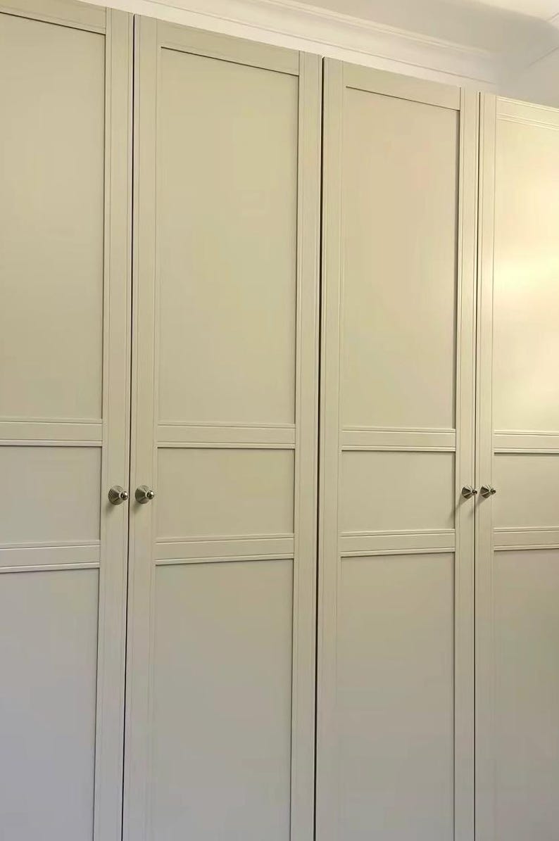 Puede incluir: Un conjunto de cuatro puertas de armario de color beige claro con un dise&ntilde;o cl&aacute;sico de estilo shaker, que presenta paneles empotrados y rieles horizontales. Cada puerta cuenta con un peque&ntilde;o pomo redondo de metal plateado.