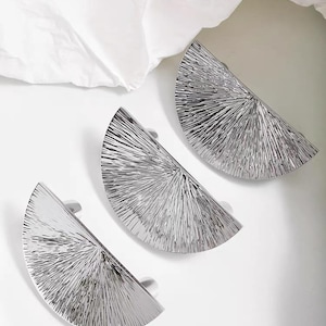 May include: Three semi-circular cabinet pulls with a polished silver finish. Each handle features a textured, radiating sunburst pattern that extends from the flat base edge to the curved outer rim, creating a reflective and metallic surface appearance.