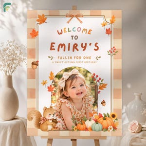 Puede incluir: Un cartel de bienvenida rectangular con borde a cuadros beige, hojas de otoño, bellotas y una ardilla. El texto dice: Welcome to Emiry's Fallin for One, a sweet autumn first birthday. Incluye una foto central de un niño o niña.