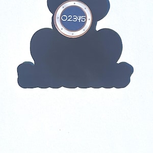 Puede incluir: Un letrero decorativo azul oscuro con la forma de la cabeza de Mickey Mouse. Tiene un elemento circular con el n&uacute;mero "02345" en blanco. El letrero est&aacute; sobre un fondo blanco.