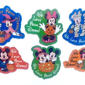 May include: Six Halloween-themed stickers featuring Mickey and Minnie Mouse in various costumes, including a witch, vampire, and mummy. Each sticker displays the text "We Love Your Door!" and depicts characters with pumpkins or candy buckets.