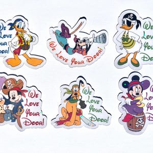 May include: Set of six Disney character stickers. Donald Duck, Goofy, and Daisy Duck are dressed as pirates. Mickey Mouse, Minnie Mouse, and Pluto are also featured. Each sticker has the text "We Love Your Door!"