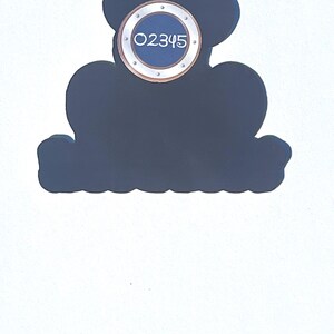 May include: A dark blue decorative sign shaped like Mickey Mouse's head. It features a circular element with the number "02345" in white. The sign is set against a white background.
