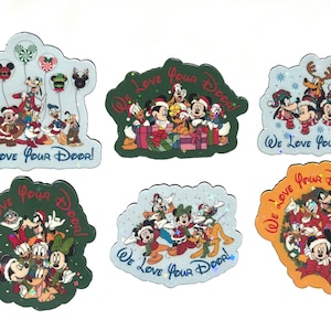 May include: Six die-cut stickers featuring Disney characters in Christmas attire. Each sticker displays the text "We Love Your Door!" and depicts various combinations of Mickey, Minnie, Donald, Daisy, Goofy, and Pluto in festive holiday scenes.