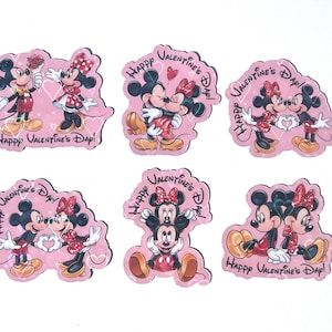 May include: A collection of six pink Valentine's Day-themed stickers featuring Mickey and Minnie Mouse. Each sticker has a different pose of the characters, with the text "Happy Valentine's Day!" in black script. The stickers are in a cartoon style.