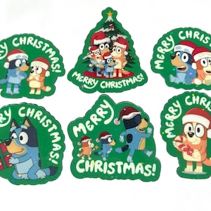 May include: A set of six green stickers featuring Bluey characters wearing Santa hats with the text Merry Christmas. The designs include characters by a tree, holding gifts, and candy canes, all with a festive holiday theme and glittery accents.