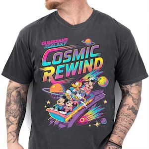 May include: Dark gray t-shirt featuring a colorful graphic of Mickey Mouse, Minnie Mouse, Donald Duck, Goofy, and Pluto on a roller coaster with the text "Cosmic Rewind" and "Guardians of the Galaxy".