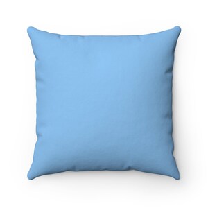 May include: A light blue square throw pillow. The pillow is made of a soft, textured fabric.