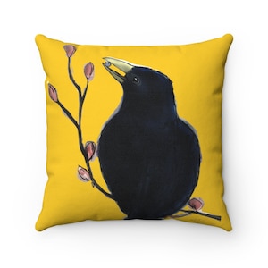May include: A black crow with a yellow beak perched on a branch with pink buds against a yellow background.