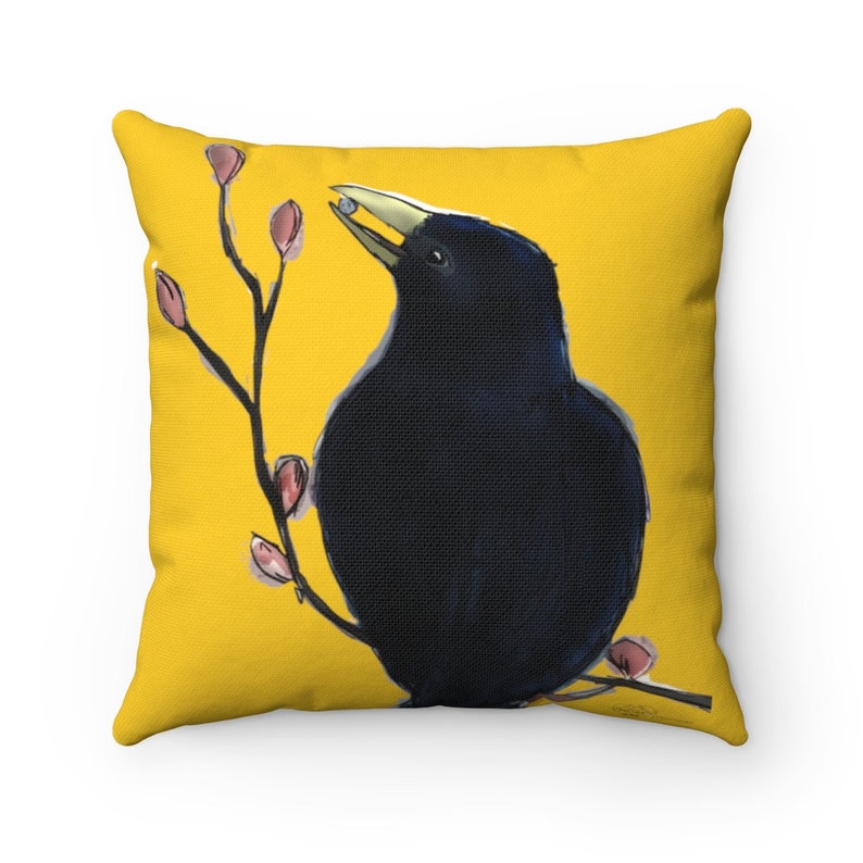 May include: A black crow with a yellow beak perched on a branch with pink buds against a yellow background.