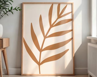 May include: A framed art print featuring a large, stylized leaf in shades of brown against a cream background. The artwork is encased in a light-colored wooden frame, creating a minimalist and modern aesthetic. The print is displayed indoors, leaning against a wall.