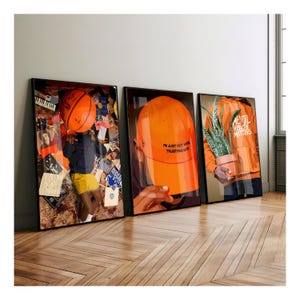 May include: Three framed art prints. The first features a person with a basketball, the second an orange hat with text, and the third a person holding a potted plant. The prints are displayed on a wooden floor.