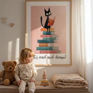 Może przedstawiać: Oprawiony obrazek przedstawiający czarnego kota czytającego książkę na stosie kolorowych książek. Pod spodem napis "let's read and dream!". Dziecko w kwiatowej piżamie siedzi na ławce z misiem i drewnianą zabawką.