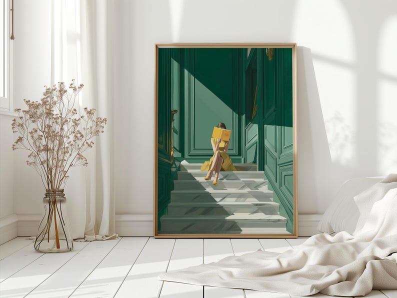 May include: A framed art print depicts a person in a yellow dress reading a book on a staircase. The background features a green door and wall with sunlight casting shadows. The artwork is displayed in a bright room with a vase of dried flowers.