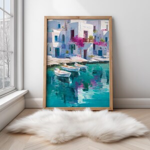 May include: A framed art print depicts a coastal scene with white buildings, blue doors, and pink flowers. Three small boats float on turquoise water. The artwork is in a wooden frame and leans against a white wall.
