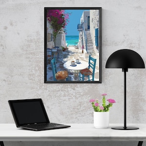 May include: A framed art print depicts a coastal scene with white buildings, blue shutters, and a turquoise sea. A table with two cups of coffee and blue chairs is in the foreground. A black desk lamp, a laptop, and a small white flower pot are also visible.