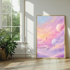 May include: A framed art print featuring a dreamy, pastel-colored space scene. The artwork depicts planets, rings, and stars set against a backdrop of pink, orange, and purple clouds. The frame is a warm gold color.