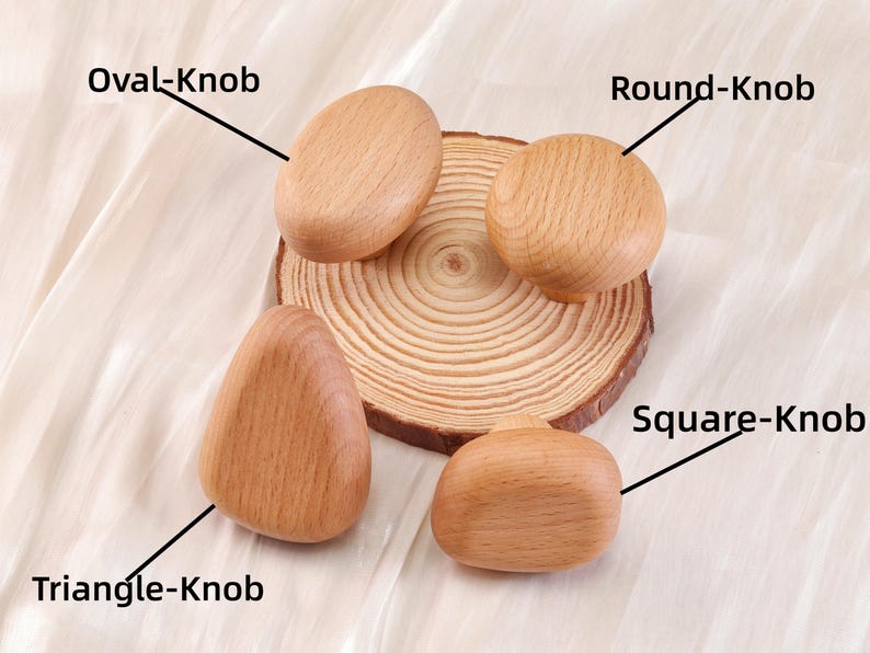 Może przedstawiać: Cztery drewniane gałki do szafek o r&oacute;żnych kształtach: owalnym, okrągłym, tr&oacute;jkątnym i kwadratowym. Gałki są jasnobrązowe i leżą na drewnianym plastrze. Etykiety tekstowe identyfikują każdy kształt gałki.