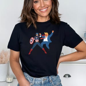 May include: A navy blue t-shirt with a graphic of Captain America and a man in a blue suit. Captain America is in a fighting stance, holding his shield. The other man is raising his arms in the air.