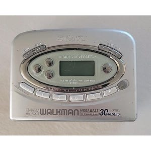 May include: Silver Sony Walkman WM-FX479 with a digital display and various control buttons. Features include FM/AM radio, Mega Bass, and 30 preset options. The device has a compact design with the "SONY" logo prominently displayed.