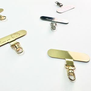 May include: Gold-toned metal phone charms with lobster clasps. Some charms have a Hello Kitty design and the phrase "I love you" engraved. Other charms are silver and rose gold.