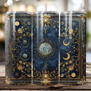 Puede incluir: Juego de tres vasos de acero inoxidable con un diseño celestial. El fondo azul marino está adornado con ilustraciones doradas de planetas, lunas, estrellas y motivos florales. Cada vaso tiene una tapa transparente y una pajita.