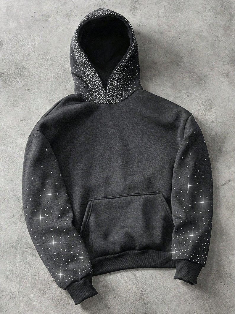 May include: A dark gray hoodie with a front pocket and a drawstring hood. The hood and sleeves are embellished with sparkling white rhinestones. The cuffs and hem are ribbed.