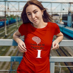 Pode incluir: Uma t-shirt vermelha com o texto "I use no AI I have the I" e um gráfico de cérebro. A t-shirt é de manga curta.