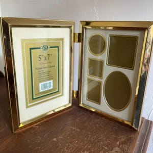 May include: A hinged, gold-colored metal picture frame. One side holds a 5" x 7" photo, the other has multiple openings in various shapes. The frame has a cream-colored matting and is labeled "Polished Brass Collection."