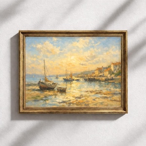 Op de afbeelding: Een ingelijst olieverfschilderij met een kusthaven bij zonsondergang. Het kunstwerk toont verschillende kleine zeilboten op kalm water, met een groep gebouwen langs de kustlijn onder een lucht vol zachte gele en blauwe wolken.