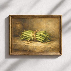Op de afbeelding: Een ingelijst schilderij toont een bos verse groene bonen, samengebonden met touw. Het kunstwerk heeft een warm, aards kleurenpalet met een rustieke esthetiek. De bonen zijn het middelpunt en rusten op een stenen oppervlak.