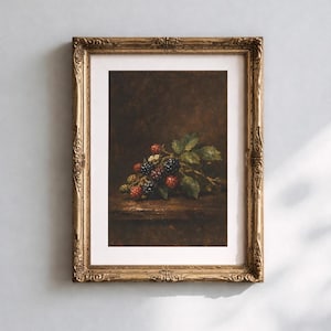 Op de afbeelding: Een ingelijste kunstdruk met een stilleven van bramen en groene bladeren. De bessen variëren in kleur van rood tot zwart. Het kunstwerk wordt gepresenteerd in een sierlijke gouden lijst, wat de esthetiek versterkt.