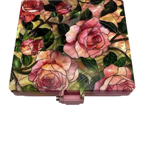 May include: A decorative box with a stained-glass design featuring pink roses and green leaves. The box has a rectangular shape with a pink clasp and a matching pink border. The floral pattern is set against a yellow background.