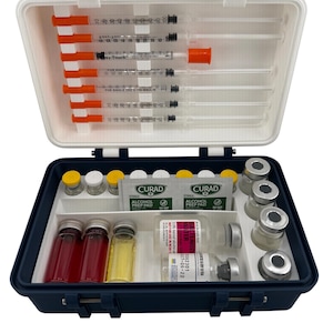 May include: An open, navy blue medical case with a white top, filled with medical supplies. The case contains syringes with orange caps, vials of liquid, alcohol prep pads, and small bottles. The text "sy-Touch" and "FOR SINGLE USE U-100 INSULIN" is visible.