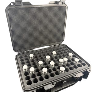 May include: A black, open, hard-shell case with a foam interior, holding multiple small glass vials with white caps. The case is designed to protect and organize the vials, likely for laboratory or medical use.
