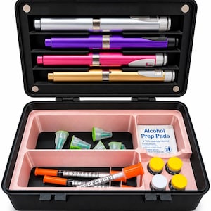 May include: A black carrying case containing four injector pens in silver, purple, pink, and gold. The bottom section holds several green-tipped needle caps, two syringes with orange caps, four small vials with yellow or white caps, and alcohol prep pads.