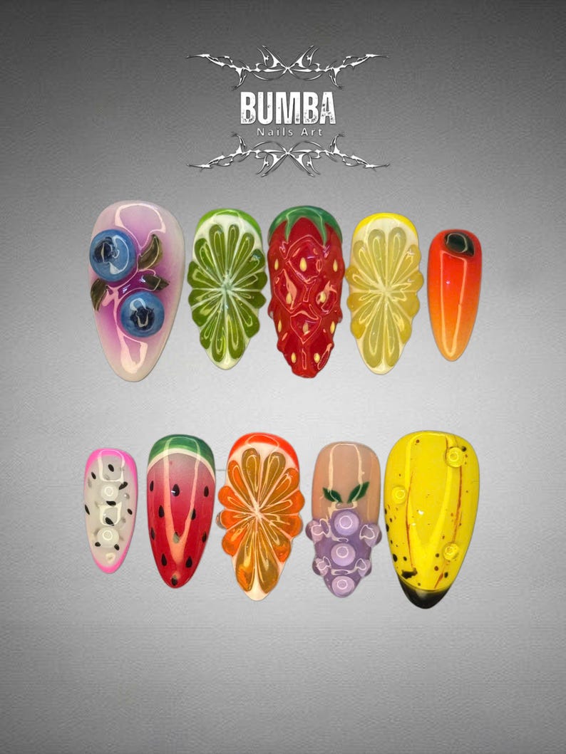 May include: A collection of ten long, almond-shaped artificial nails with vibrant fruit-themed designs. The designs include blueberries, lime, strawberry, lemon, orange, dragon fruit, watermelon, and grapes. The nails are set against a gray background, with the text "BUMBA Nails Art" at the top.