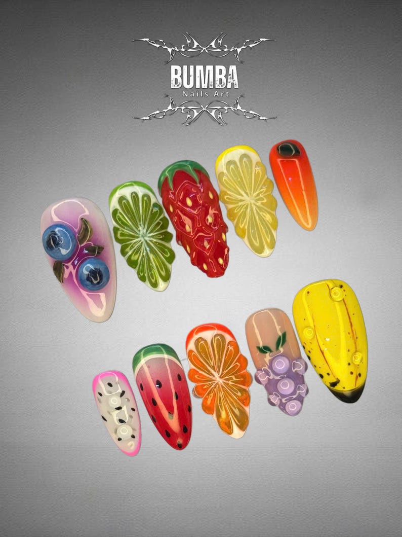 May include: A set of ten acrylic nails with fruit designs. The nails feature detailed illustrations of blueberries, limes, strawberries, lemons, oranges, watermelons, grapes, and bananas. The text "BUMBA Nails Art" is at the top.