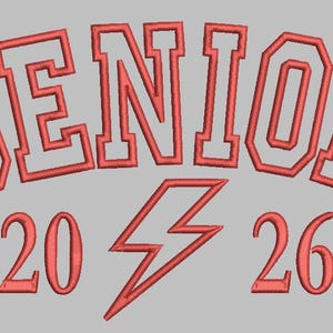 May include: Red embroidered design on a gray background. The word "SENIOR" arches across the top, with "20" and "26" below, and a lightning bolt in between. The design is likely for a graduation.